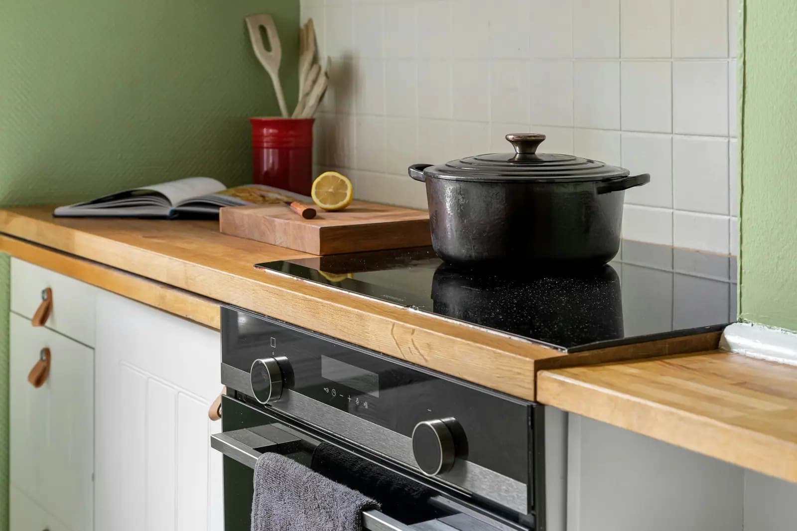Smooth glass cooktop with a cast-iron pot, set in a wood counter above an oven