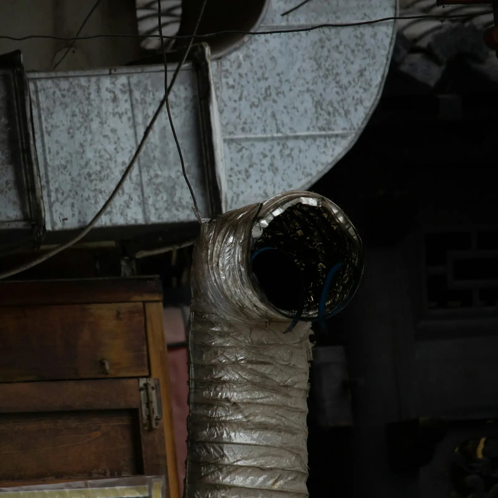 Sagging flexible foil duct with dust buildup in a cluttered utility space