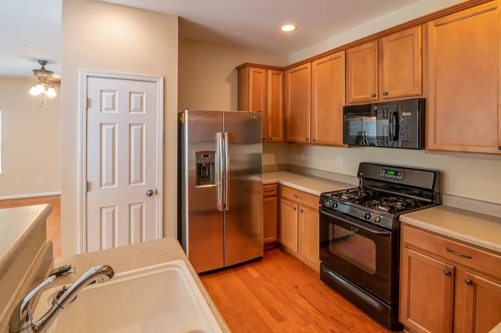 Kitchen with wood cabinets, a stainless side-by-side refrigerator, and a black gas range