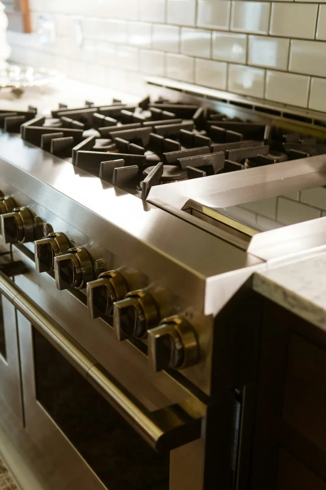 Front-control knobs on a stainless gas range beside a marble counter