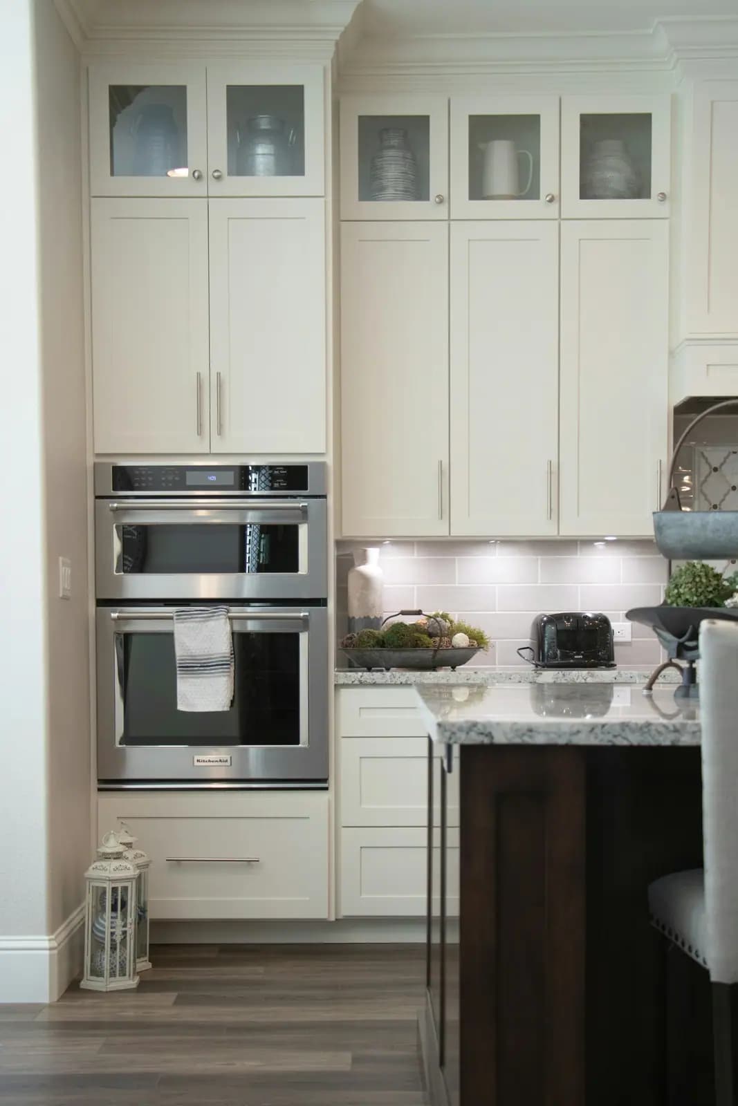 Stainless microwave and wall oven stacked in white cabinetry
